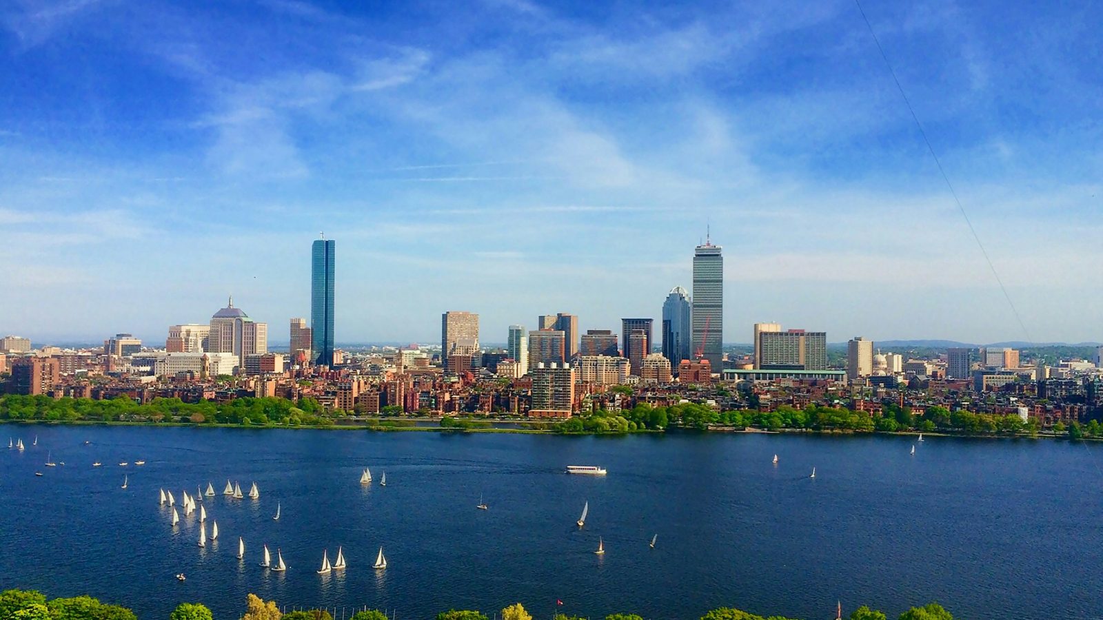 The Boston skyline of Back Bay with the John Hancock and Prudential towers, seen across the Charles River with sailboats on the water