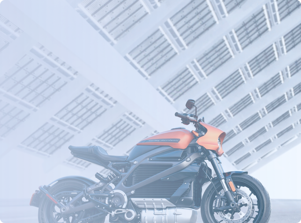 Черно-бронзовый мотоцикл стоит на стоянке у серого бетонного здания, вид сбоку