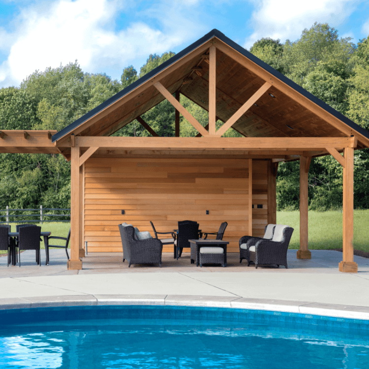 Eine gaubenähnliche Terrassenüberdachung aus Holz neben einem Pool, es sind mehrere Gartenmöbel sichtbar