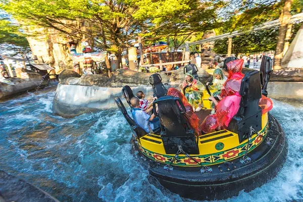 Круглая лодка с пассажирами в дождевиках на бурном водном аттракционе Dream World