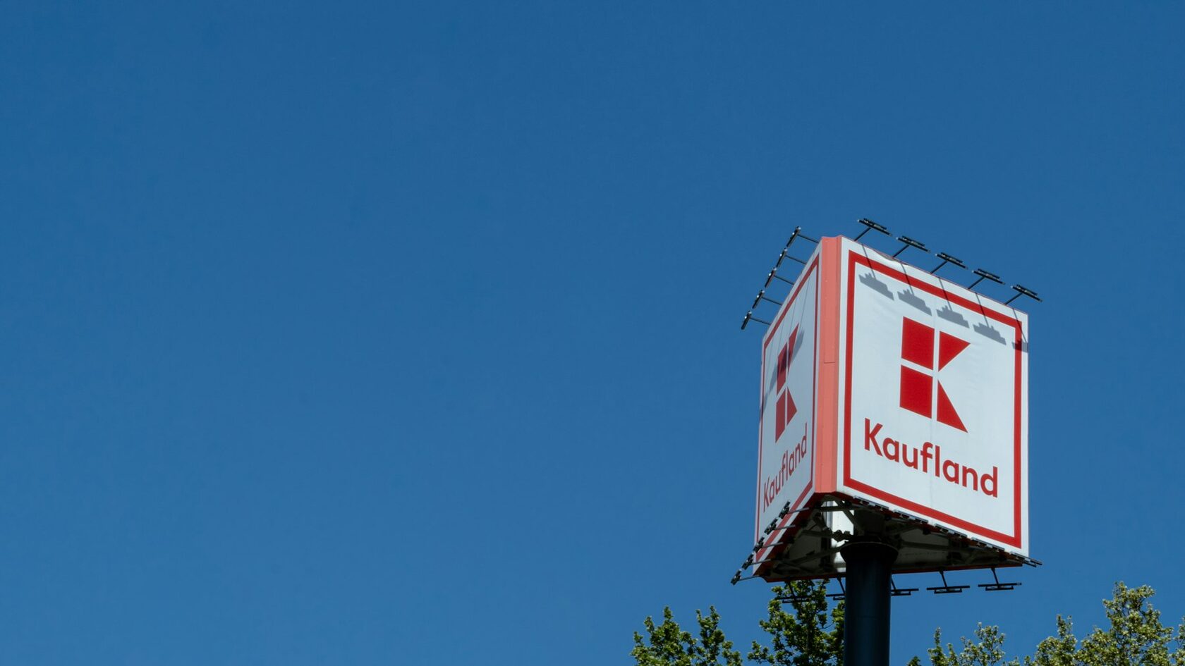 A red and white Kaufland sign against a blue sky