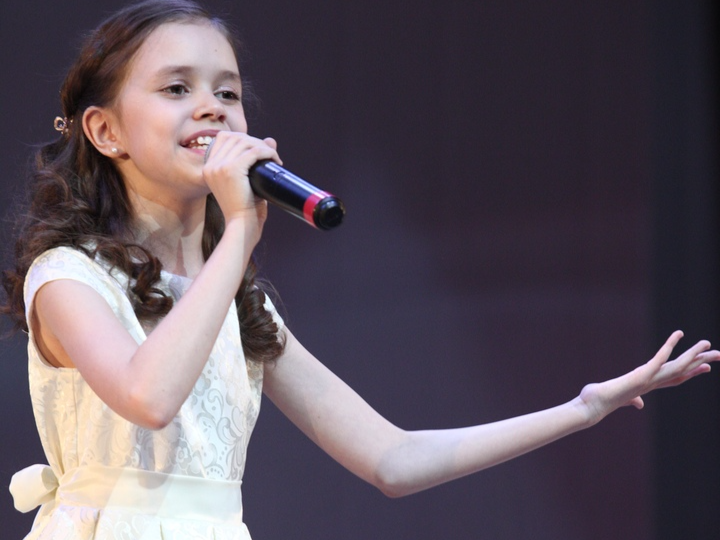 Девочка поёт в микрофон на сцене фото