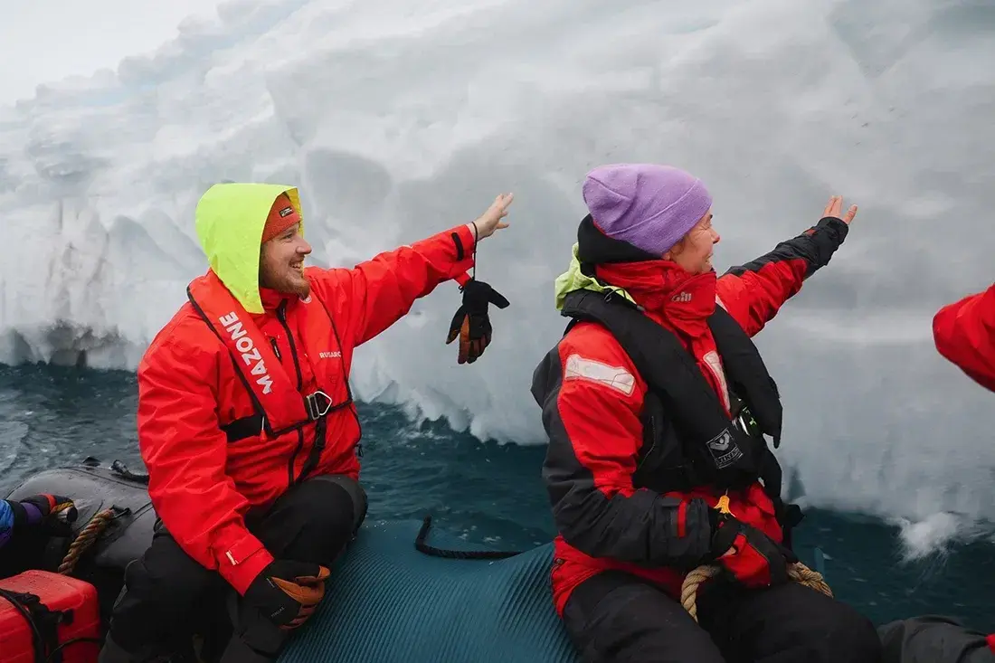 Travelers in a Zodiac boat exploring a towering Antarctic iceberg during a small-group sailing expedition