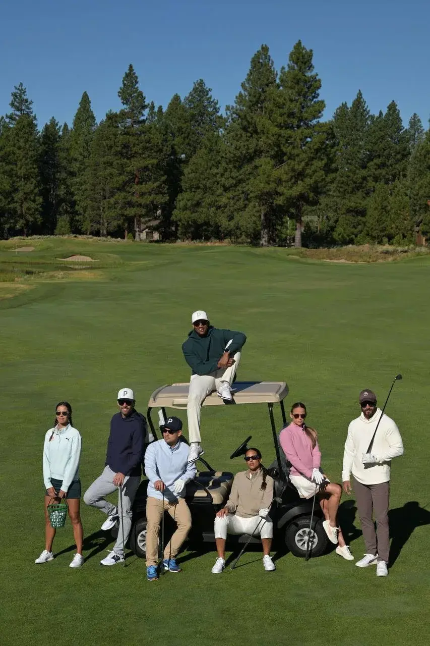Участники Leaders Golf Cup рядом с гольф-каром на поле.