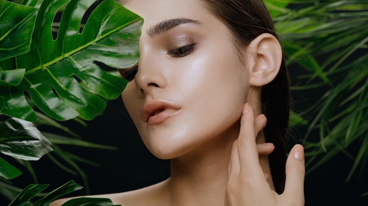 Элегантная девушка с ухоженной кожей, окруженная зелеными листьями, символизирует натуральность и высокое качество косметики Leaf Code