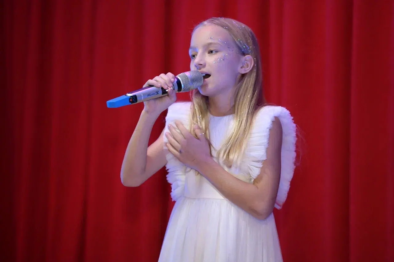 Девочка поет в микрофон на сцене