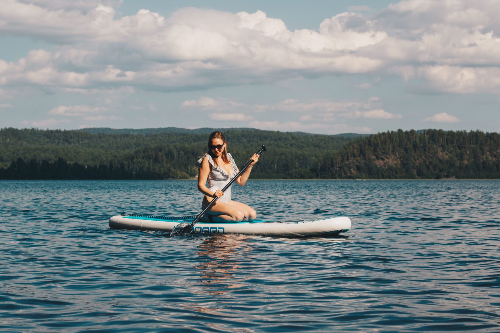 Девушка плавает на сапе на озере Аракуль