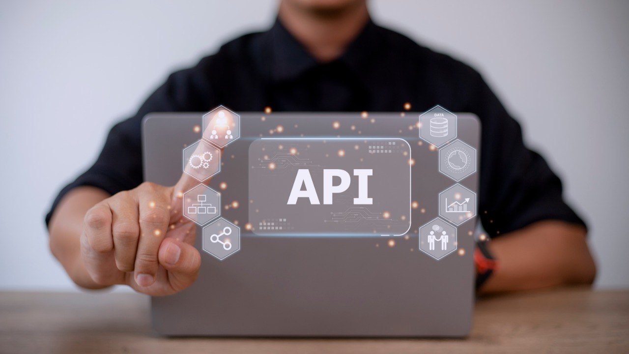 Мужчина нажимает на иконку API на экране планшета — интеграция API для поиска и бронирования авиабилетов