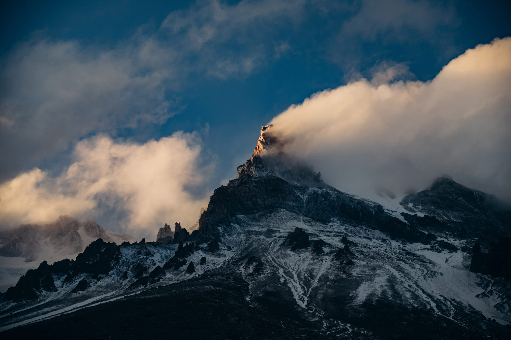 Kazbek's dark summit pyramid wrapped in evening clouds