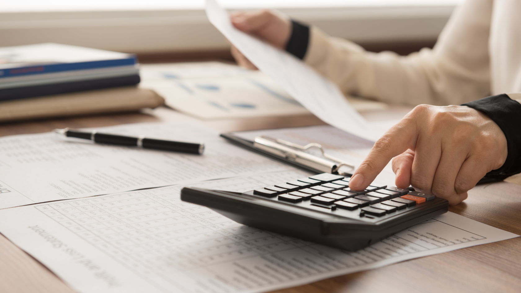 A business professional with a calculator and paperwork working on capital management.