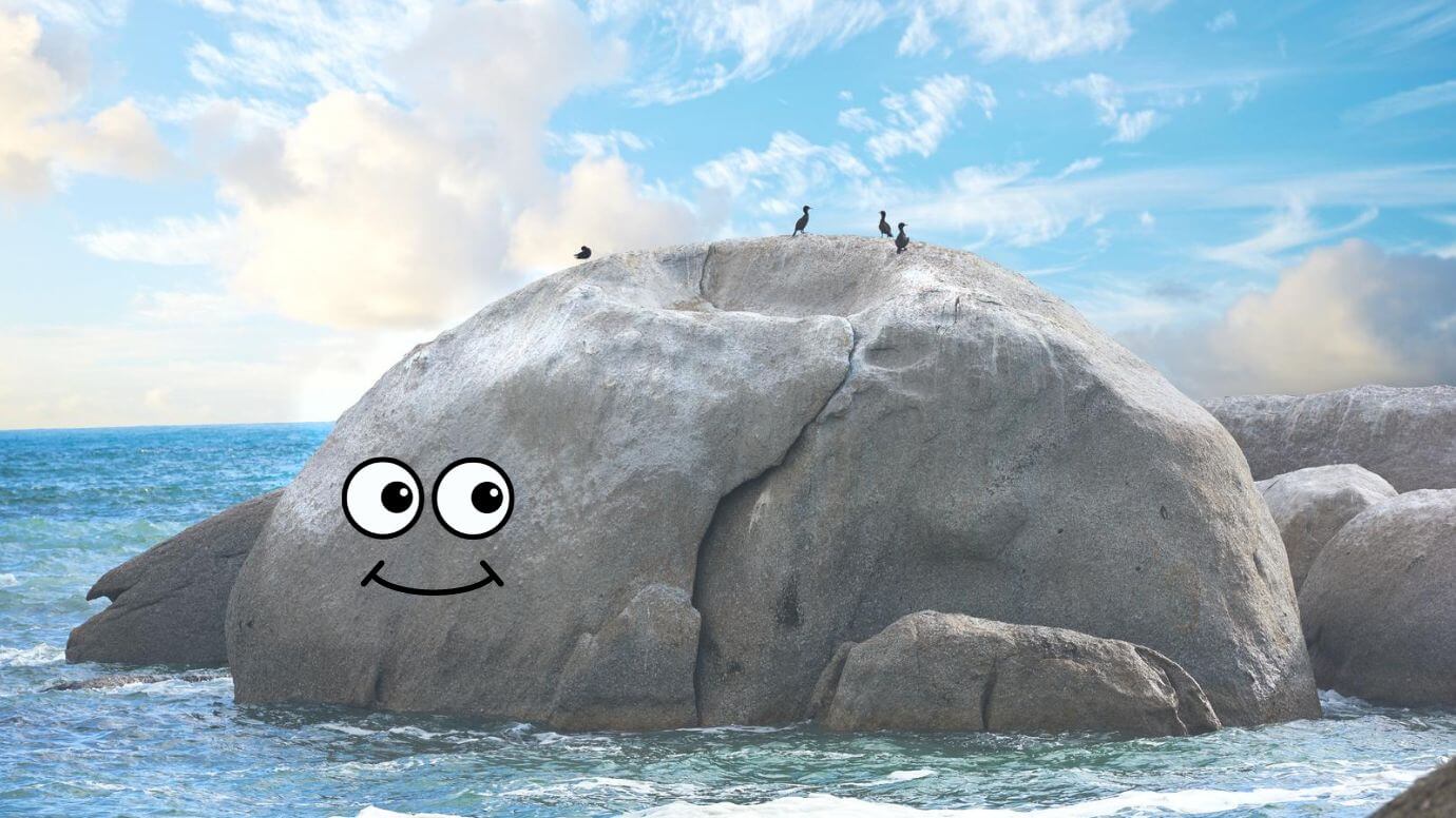 An enormous grey rock with playful cartoonish eyes, located in the sea