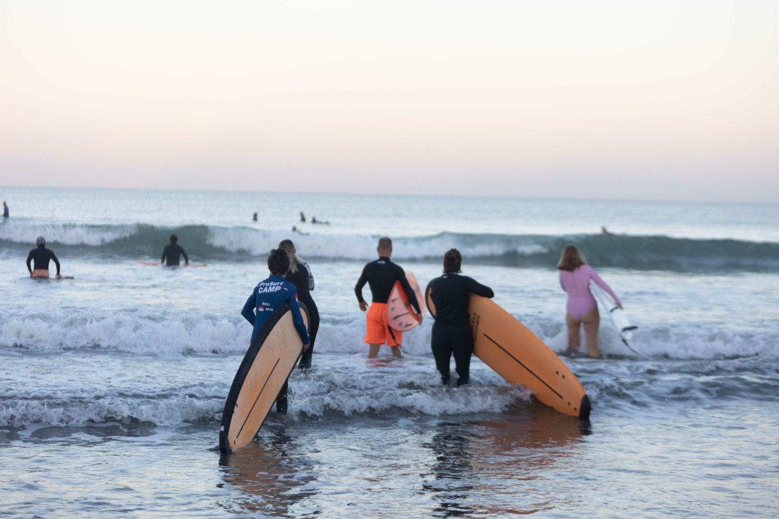 Группа ProSurf Camp с досками заходит в океан на рассвете