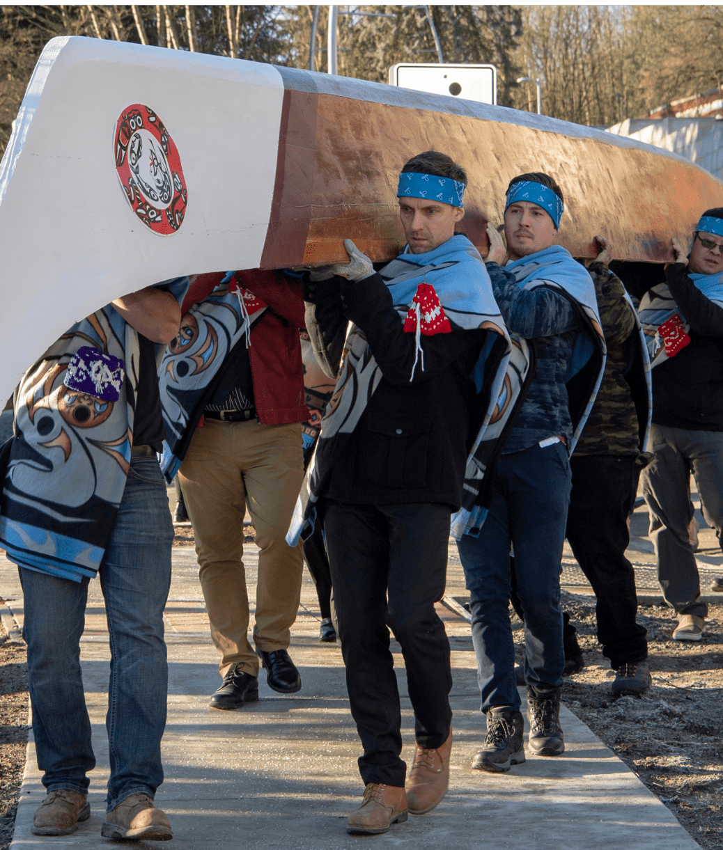first nation people carrying canoe 