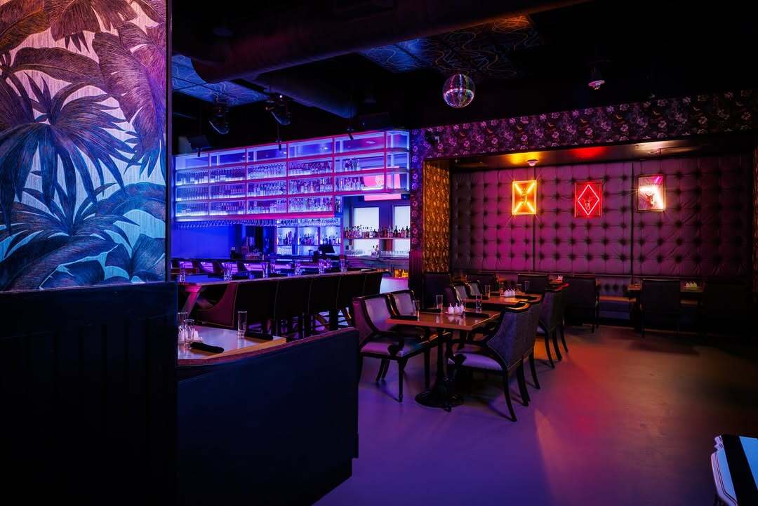 Intimate neon-soaked interior with tropical wallpaper at Nirvana, a hidden gem late night lounge in Seminyak.