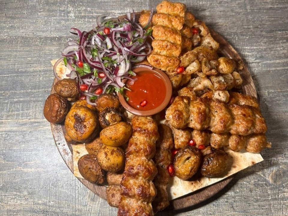 Ассорти шашлыков с луком и соусом на большом блюде