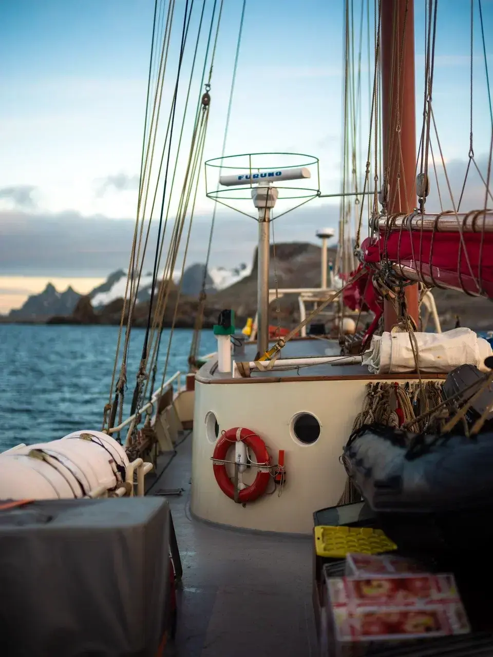 Sailing vessel navigating Antarctic waters with snow-covered mountains in the background during a small-group Antarctica expedition.