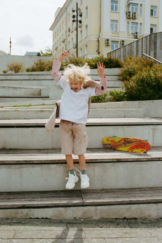 мальчик прыгает в бежевом спортивном костюме