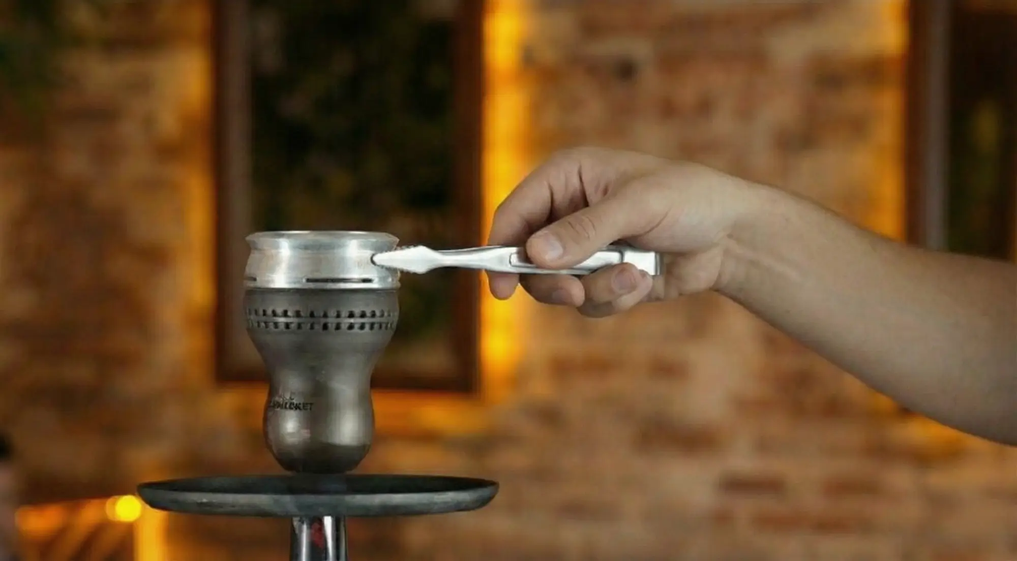 Using tongs to place a heat management device (HMD) onto the hookah bow