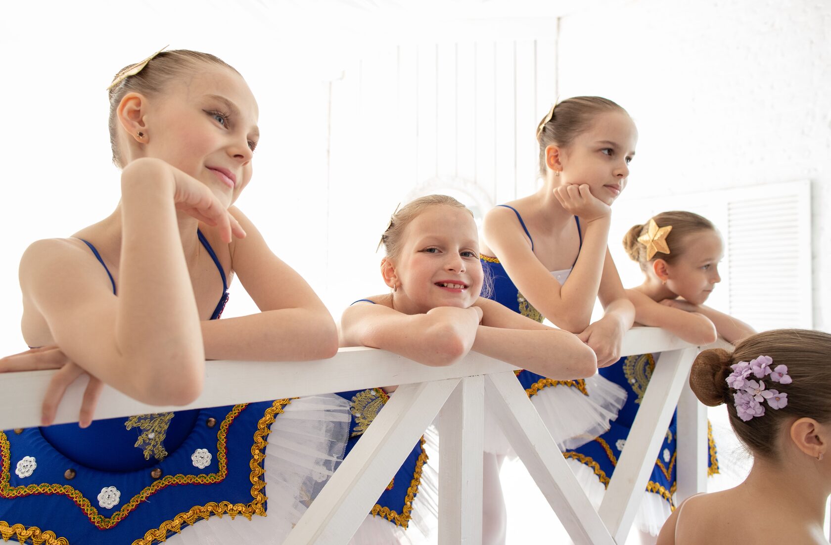 Девочки в балетных пачках облокотились на перила
