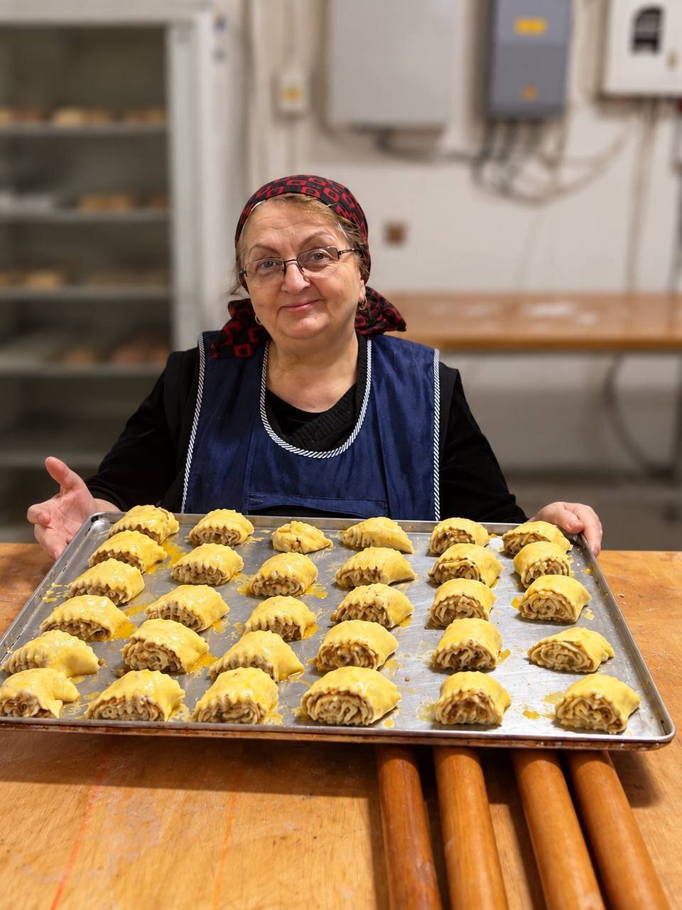 Мама Зураба в цеху пекарни «Вкусный мир» с подносом пирогов