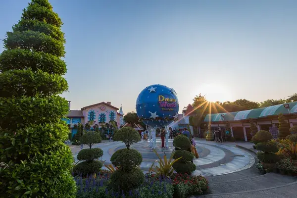 Синий глобус Dream World на площади парка в лучах заката и сад