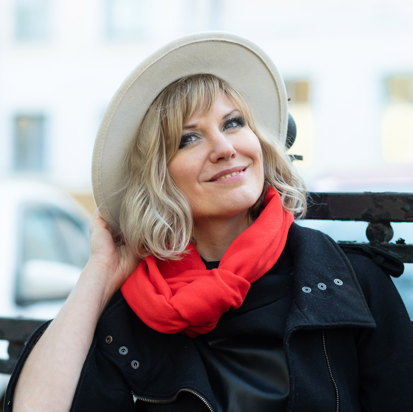 Улыбающаяся девушка в черной шляпе с красным шарфом.