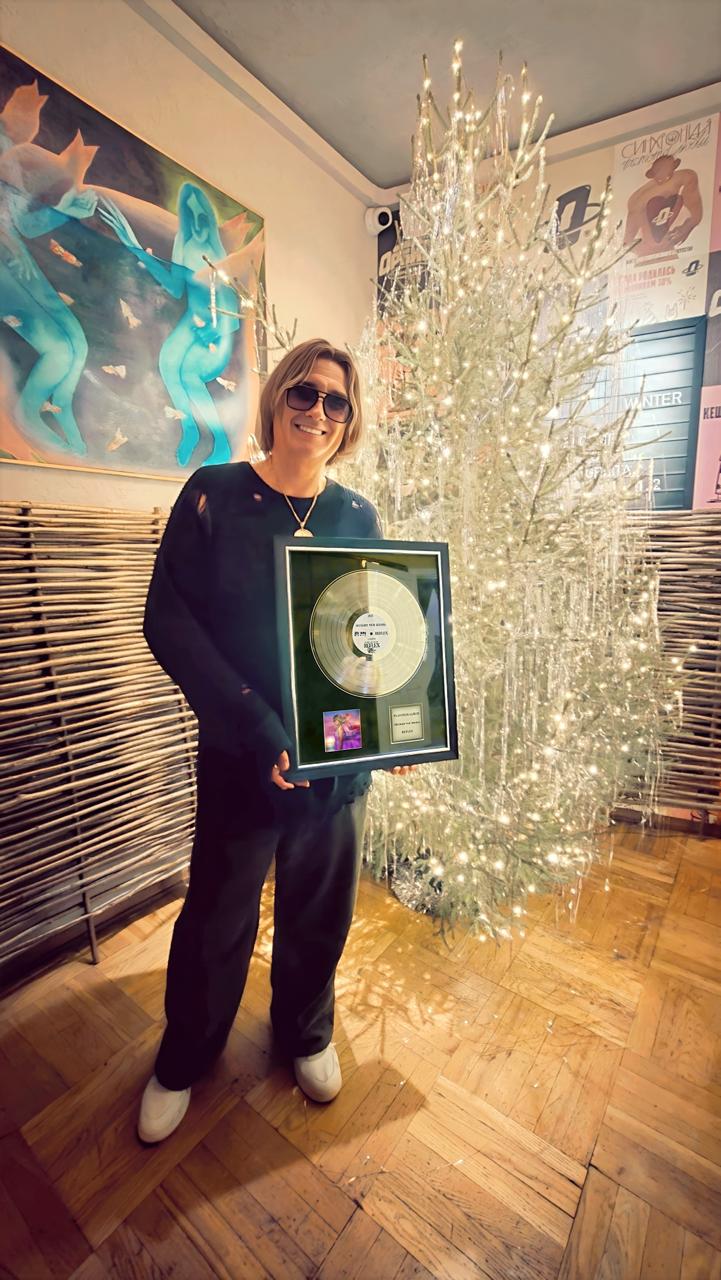 Вячеслав Тюрин держит платиновый диск альбома «Больше чем жизнь» группы REFLEX в интерьерном пространстве; награда вручена лейблом Zion Music за высокие цифровые показатели и многомиллионные прослушивания.