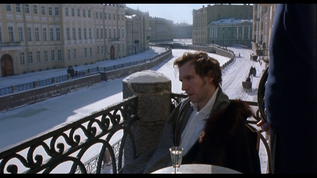 Отвергнутый Татьяной, Онегин-Файнс депрессует с рюмкой на столе, сидя на балконе дома 25 по набережной Мойки. На заднем плане – музей-квартира Пушкина.