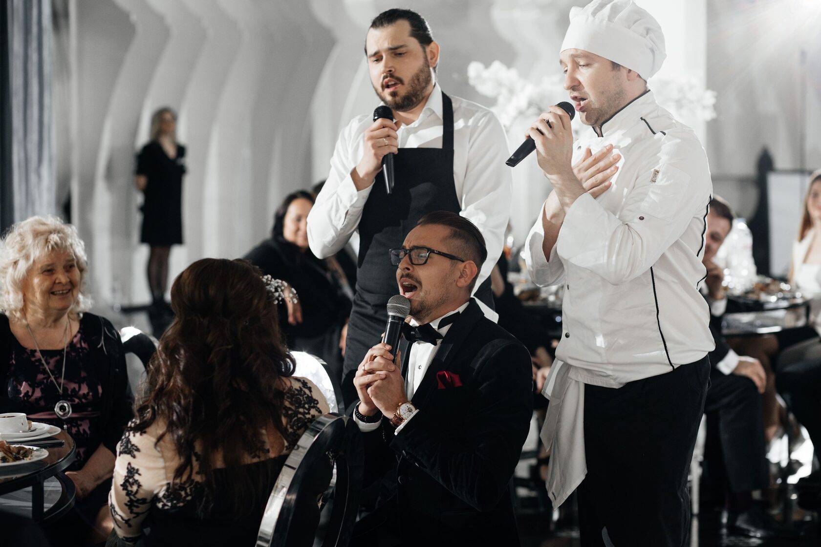 Официанты и повар поют гостям