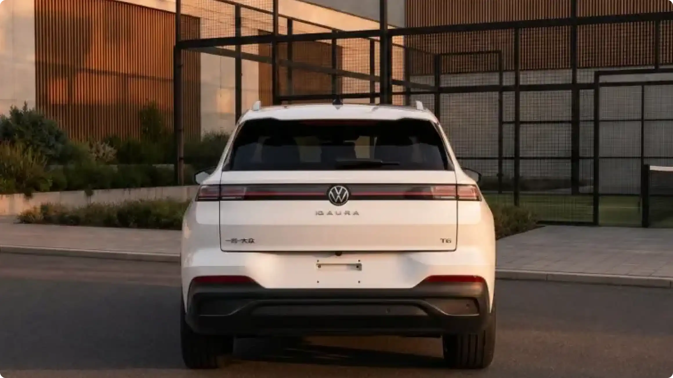 Volkswagen ID. Aura T6 в белом цвете, вид сзади: светодиодная полоса, логотип VW, лидар на крыше и скрытые дверные ручки.