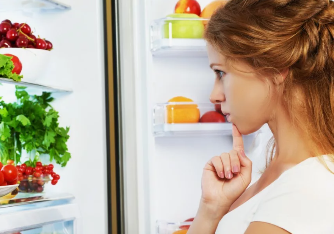 Постоянный голод в желудке. Девушка у холодильника. Чувство голода. Девушка заглядывает в холодильник. Стресс на диете.