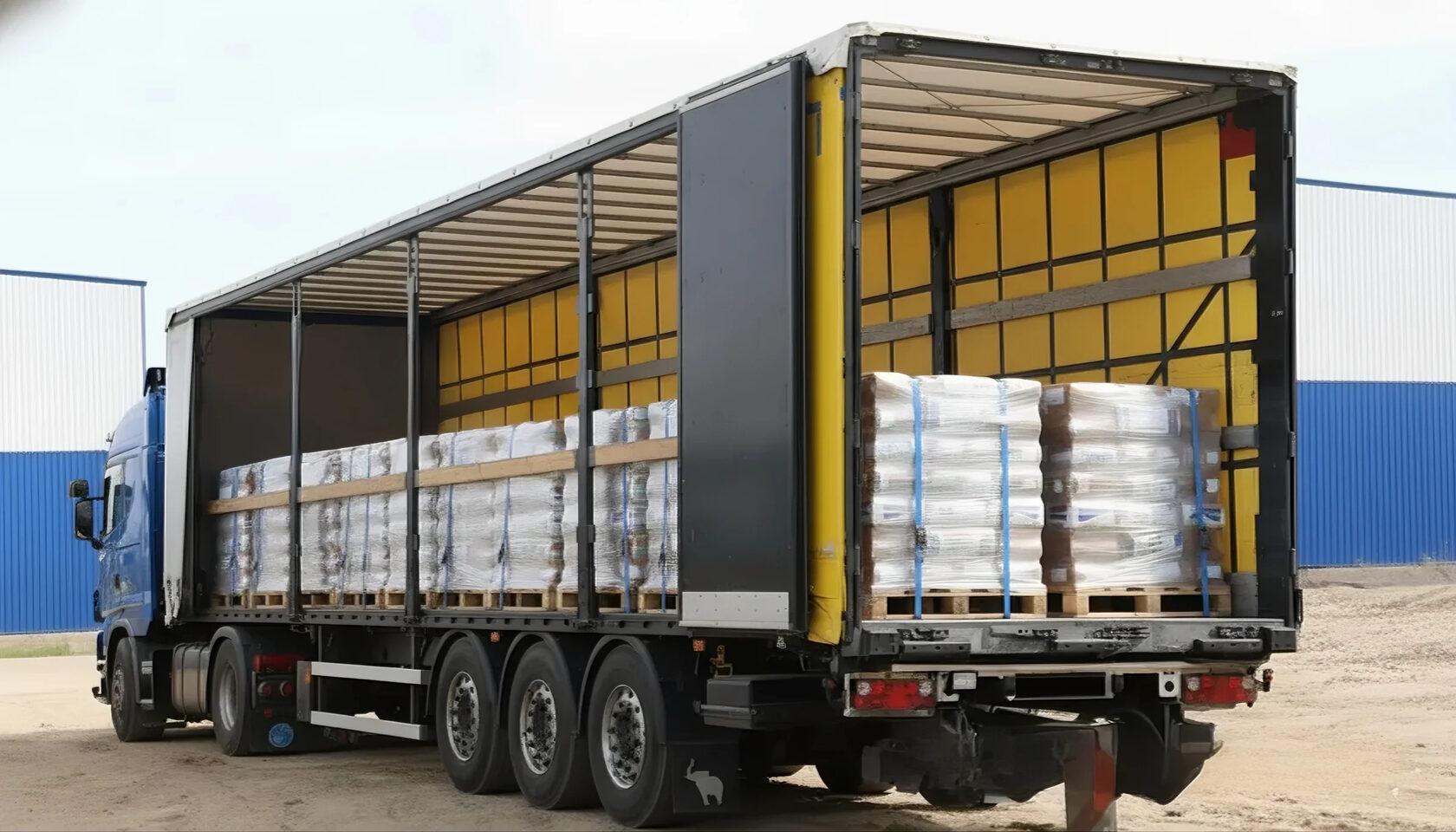 Полуприцеп с открытым бортом и загруженный паллетами гружеными