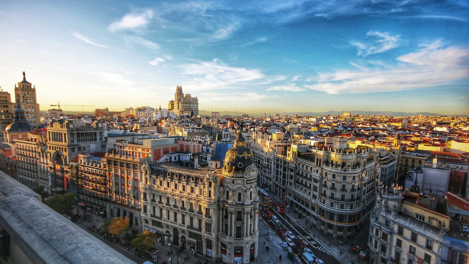 Rooftop view of central Madrid with the domed Metrópolis building at the start of Gran Vía and the city's rooftops stretching to the mountains