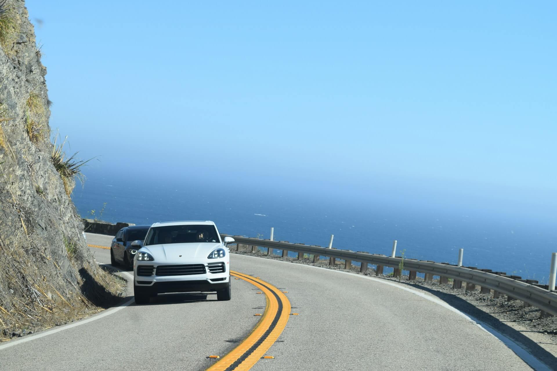 Две машины на дороге на фоне моря