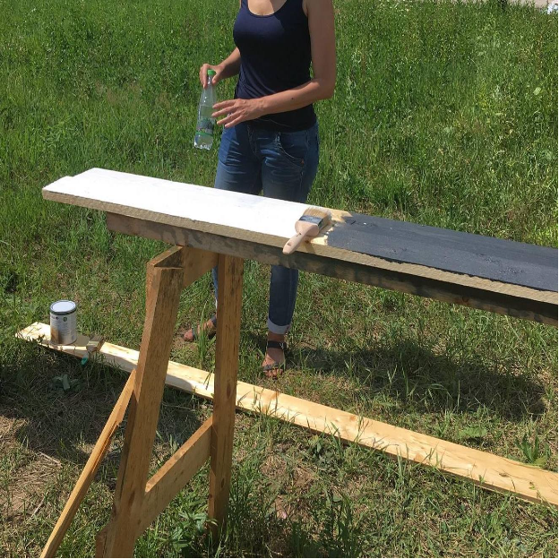 Девушка на зелёной траве устроила перерыв во время покраски