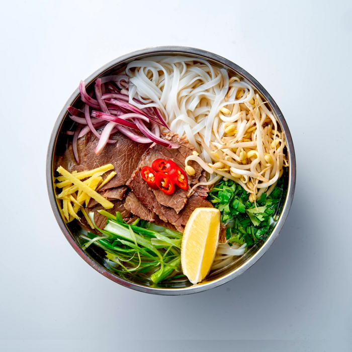 Фо бо с говядиной, рисовой лапшой, зеленью и лимоном в Lao Lee.