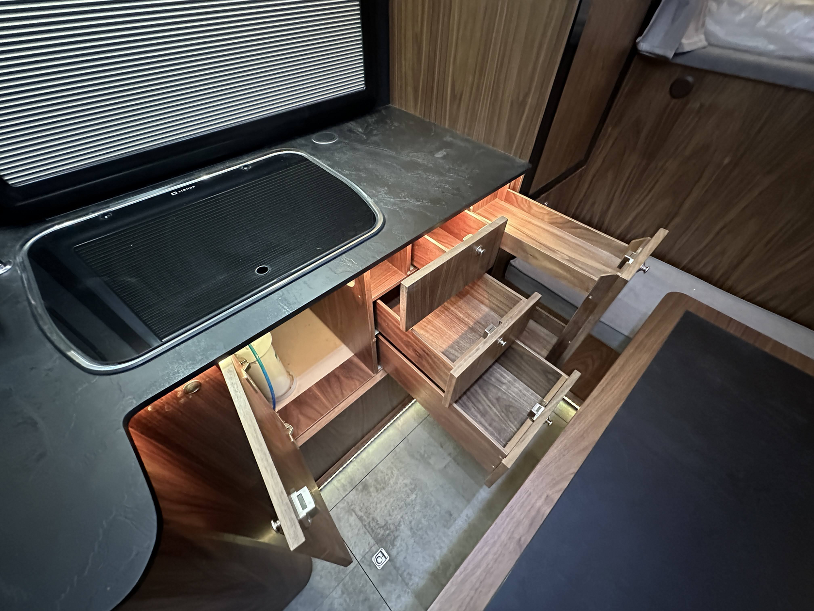 Интерьер кухни в Piligrim Camper 500LX: глубокая мойка, столешница и шкафы для хранения посуды