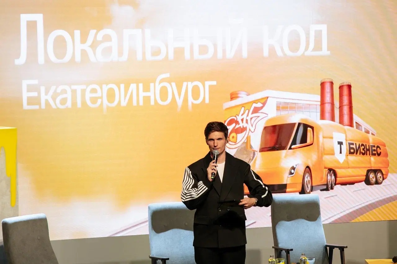 Модератор с микрофоном на фоне экрана «Локальный код. Екатеринбург»