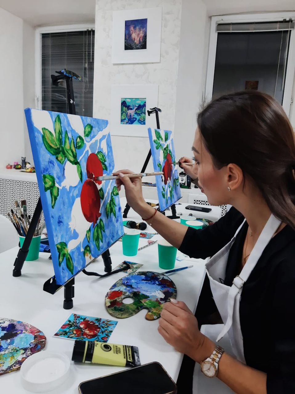 Участница рисует яркую картину за мольбертом