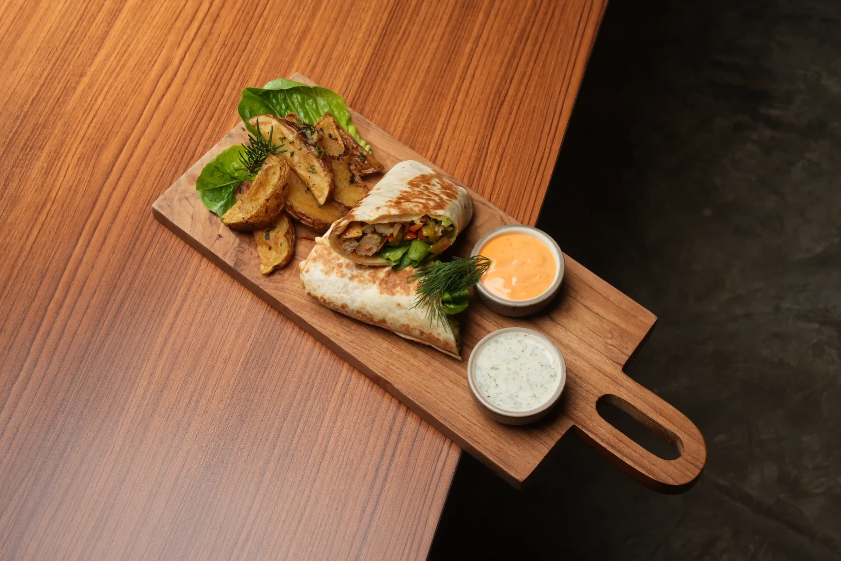 Grilled chicken shawarma wrap with vegetables, hummus, tzatziki, potato wedges, and dipping sauces