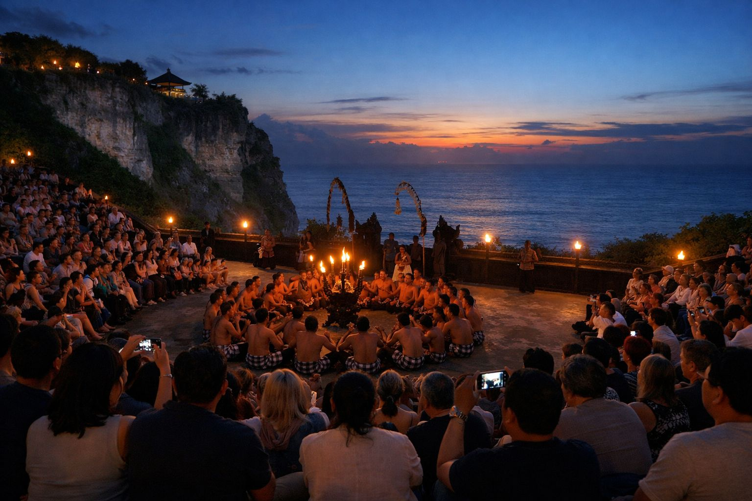 Suasana penonton menyaksikan Tari Kecak di Pantai Melasti Bali pada awal malam dengan panggung terbuka di tepi laut