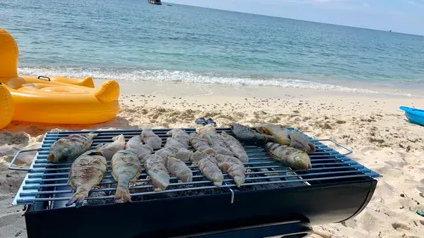 Рыба на мангале у самой кромки воды на пляже