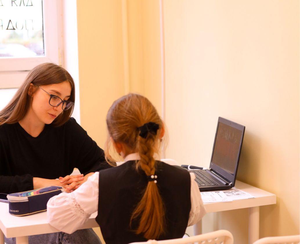 Преподаватель английского Софья Скворцова на уроке с ученицей, что-то пишут, справа ноутбук