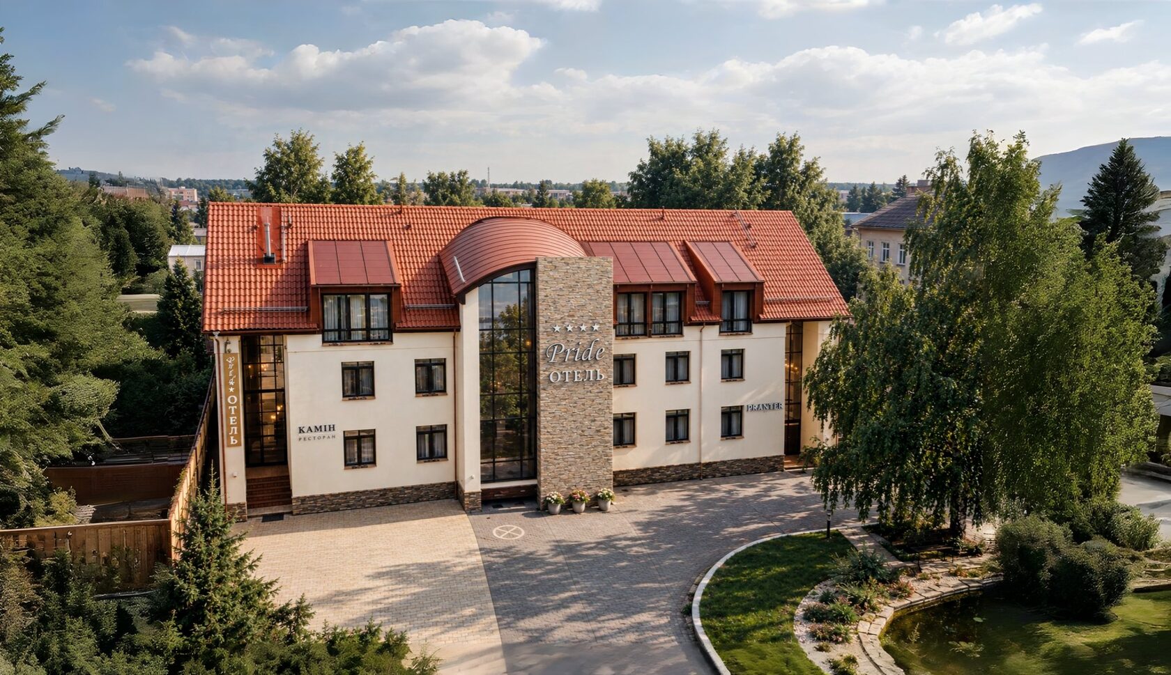 Здание Pride Hotel и ресторана «Камин»: парадный въезд, газон и пруд