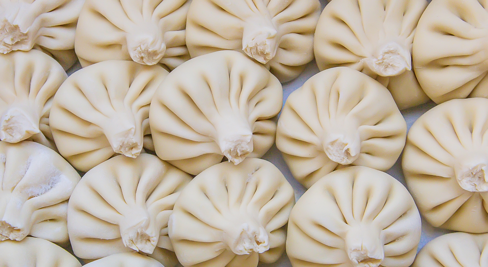 Freshly shaped Georgian khinkali on a floured kitchen surface