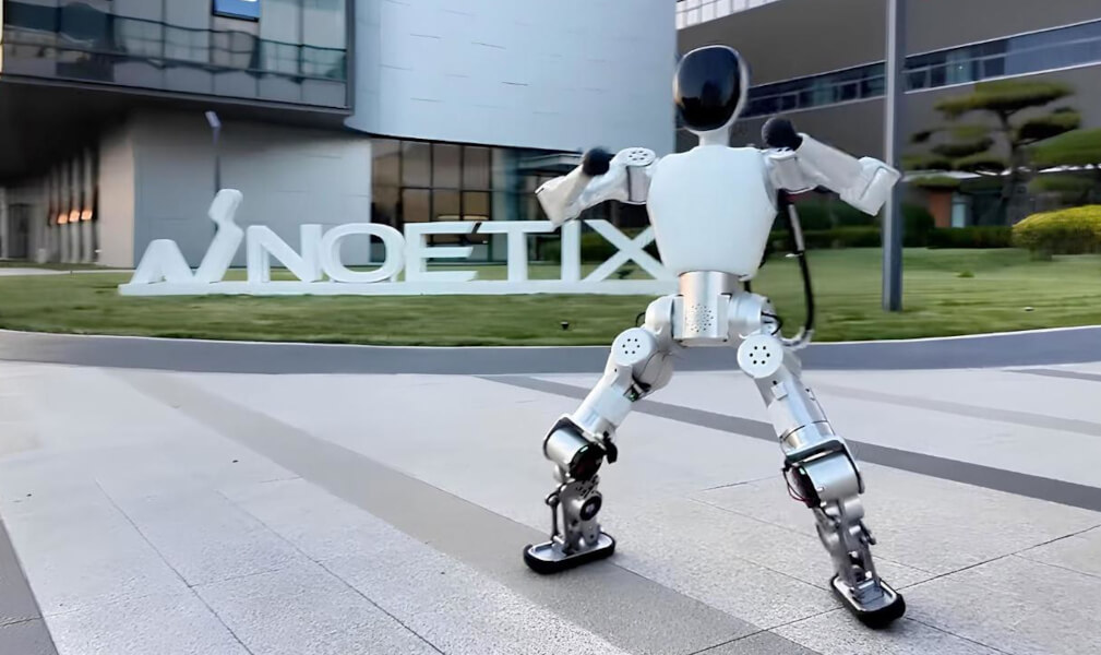 Робот-гуманоид Noetix Bumi рядом с гостем мероприятия — сравнение роста