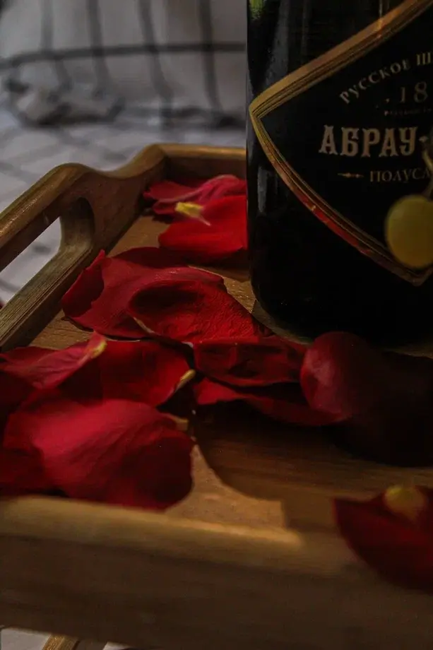 Деталь романтического оформления в домике глэмпинга Тишина: шампанское Абрау-Дюрсо с лепестками роз — услуга Romantic Home для двоих в лесу Перми
