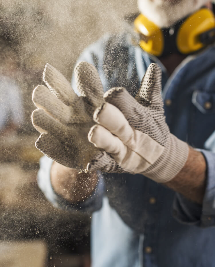 Ein Handwerker klopft seine Arbeitshandschuhe aus