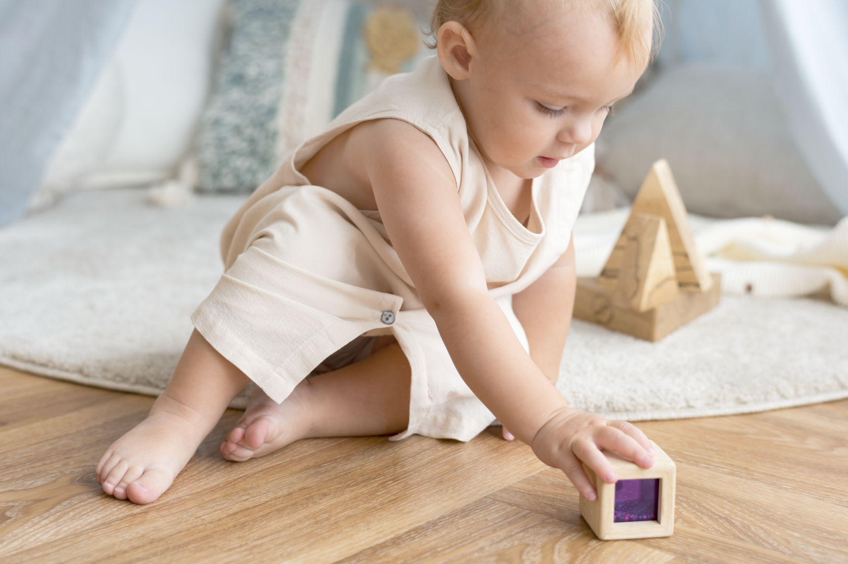 A baby plays with sensory-rich household items, supporting early learning, motor development, and attachment through playful interaction.