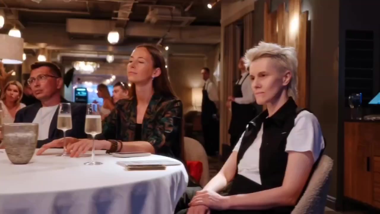 Гости сидят за круглыми столами с бокалами на вечернем мероприятии в ресторане — кадр из видеоотчёта